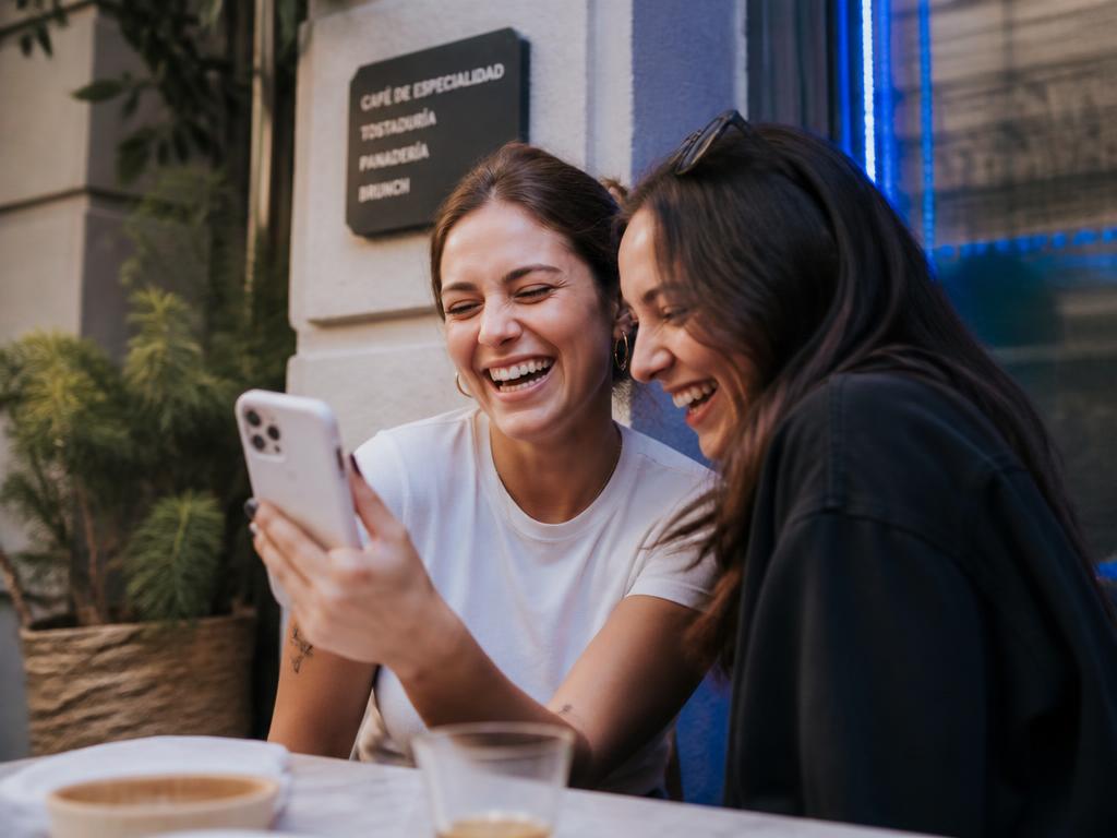Dos amigas riéndose mientras miran la app de Renters en el celular